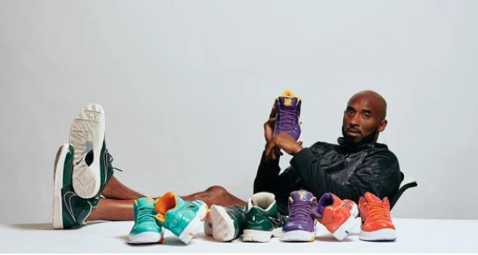 Kobe Bryant sitting down, holding a pair of Nike UNDEFEATED Kobes