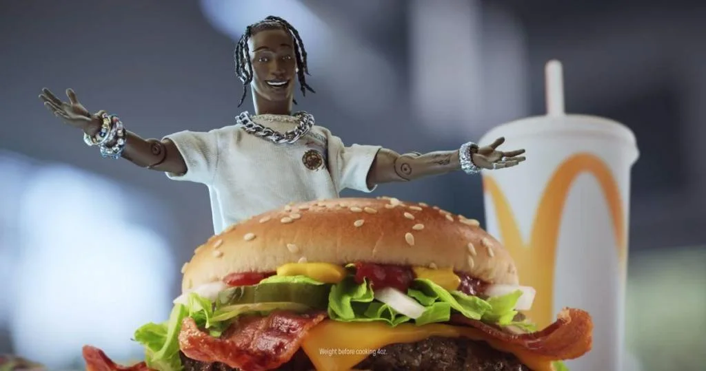 an action figure of Travis Scott presenting a Mcdonalds burger